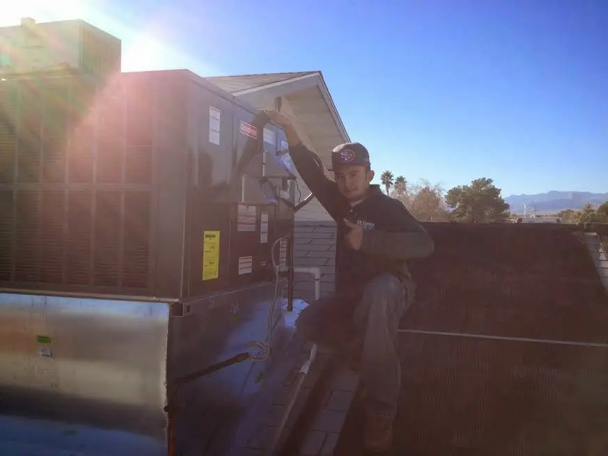 HVAC technician performing Air Duct Cleaning on a rooftop unit in Castle Pines